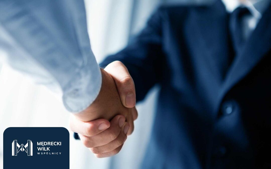 Uścisk dłoni dwóch osób w garniturach, symbolizujący zawarcie ugody lub porozumienia. W lewym dolnym rogu logo kancelarii Mędrecki Wilk i Wspólnicy.